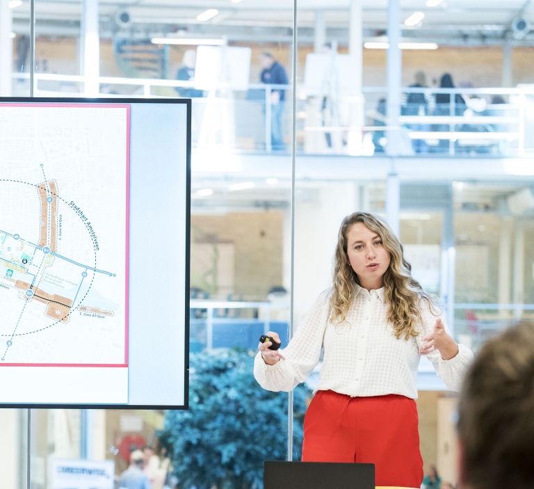 women with a white blouse and red pants presenting.